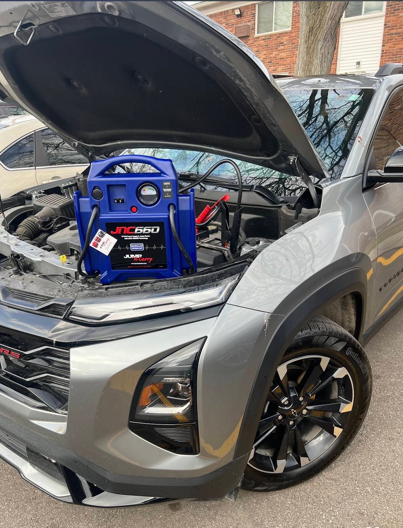 Portable jump starter connected to a silver SUV battery