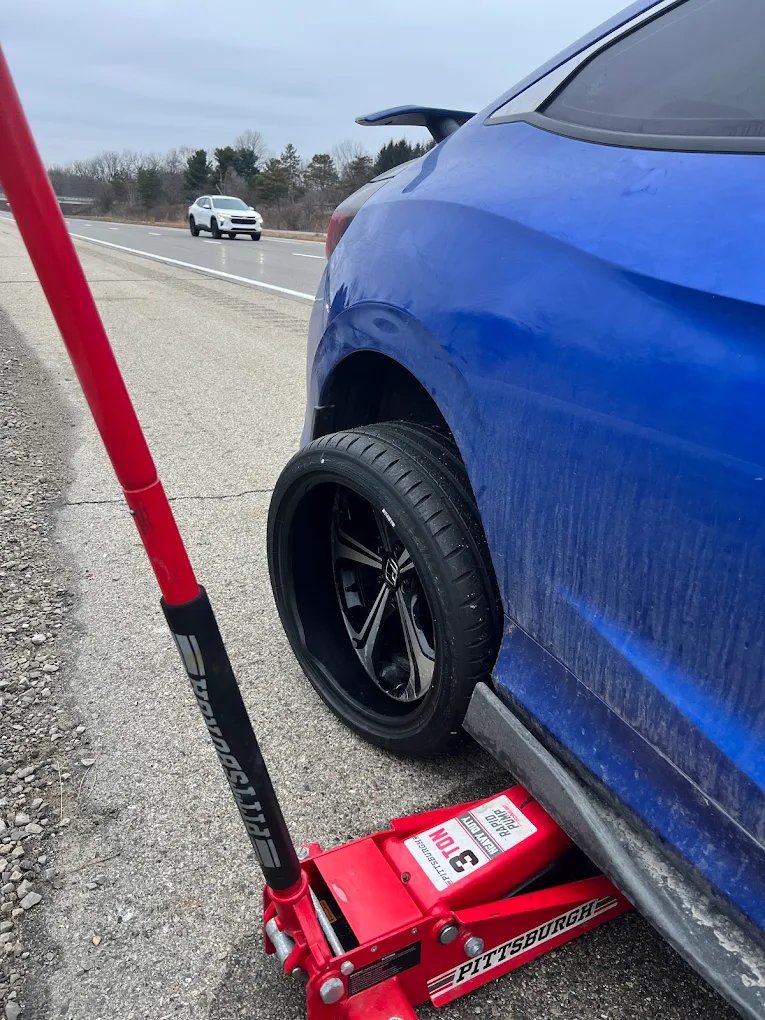 Blue car raised on a jack during tire service