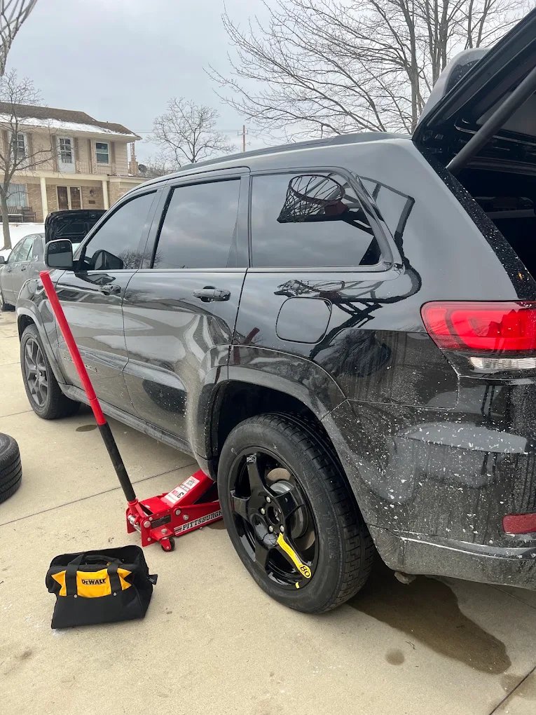Dark SUV raised on a jack for tire service